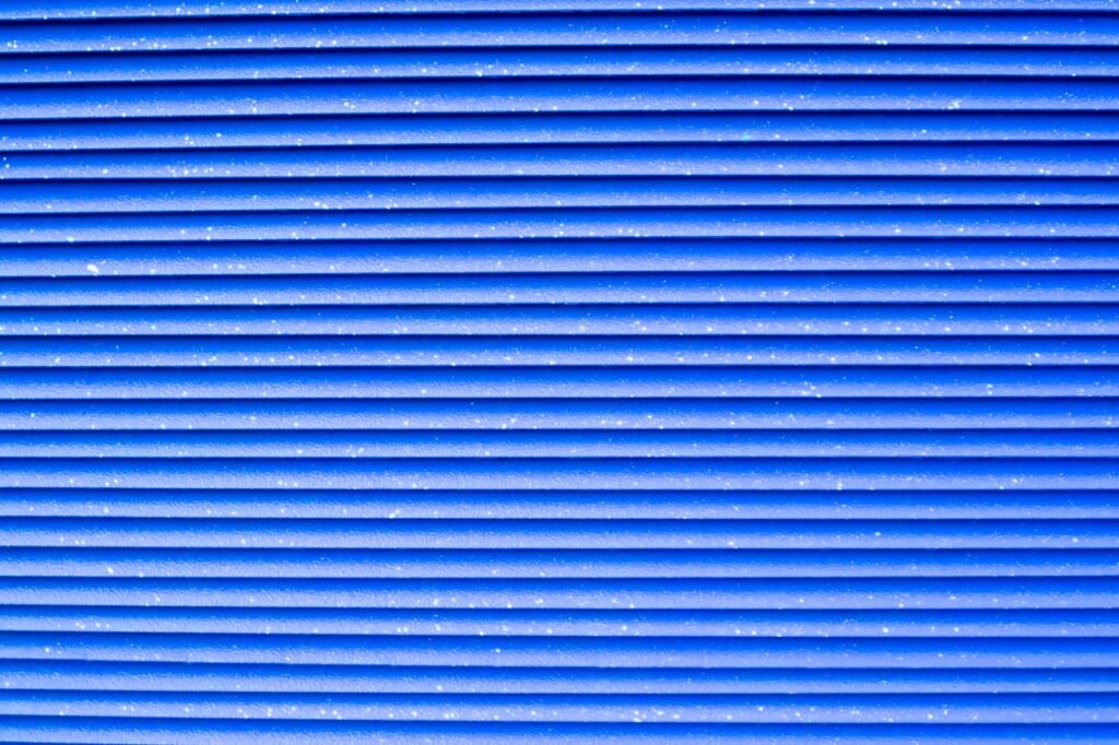 Close-up of a vibrant blue corrugated metal texture with repetitive patterns.